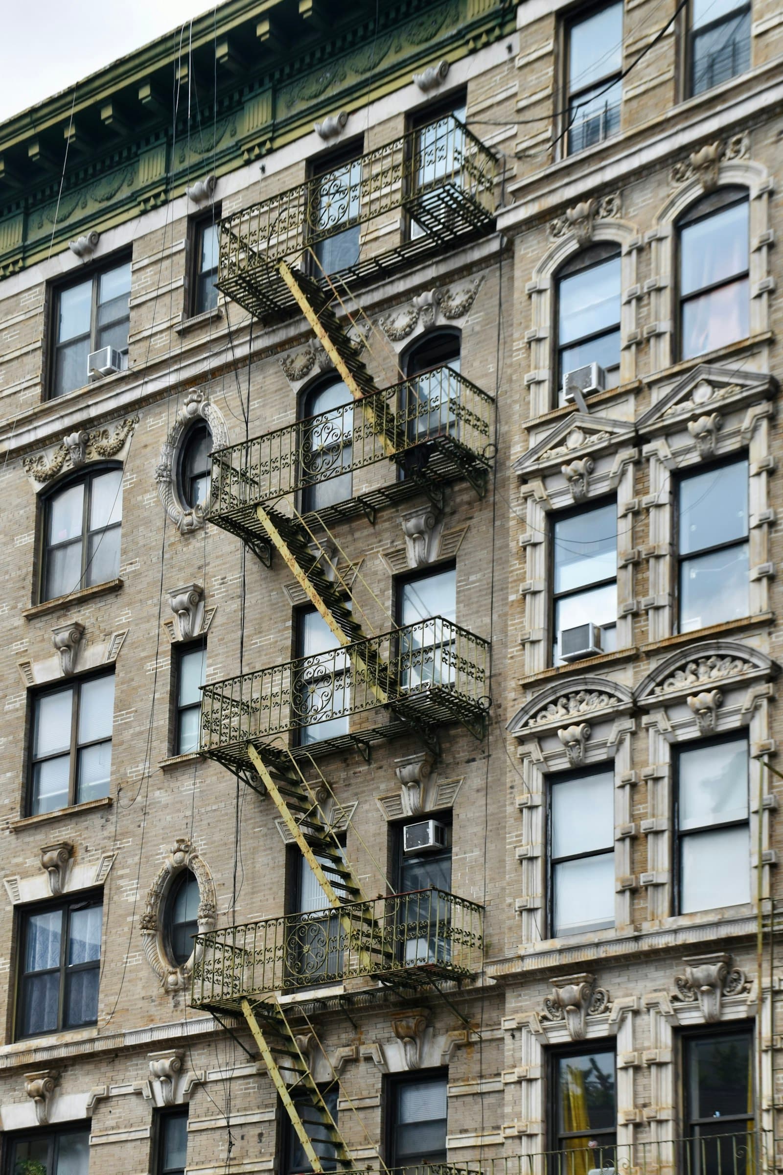 NYC apartment building facade with fire escapes in late-afternoon light