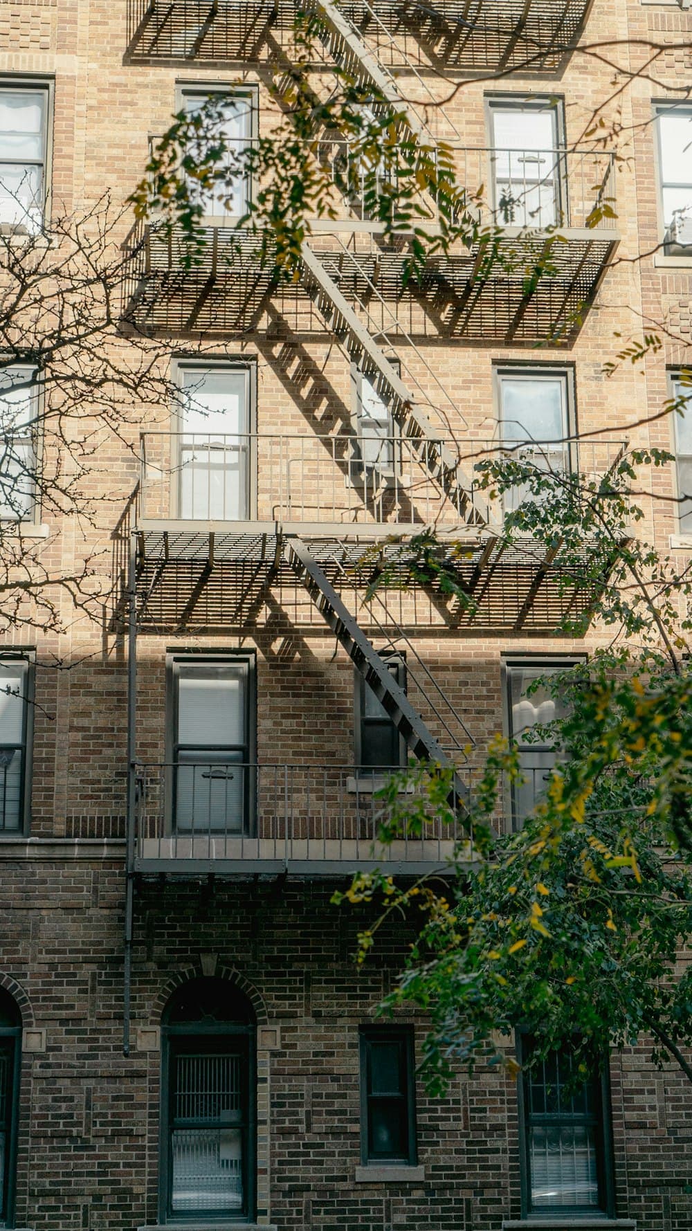 A sunlit prewar brick apartment building with a fire escape in New York City